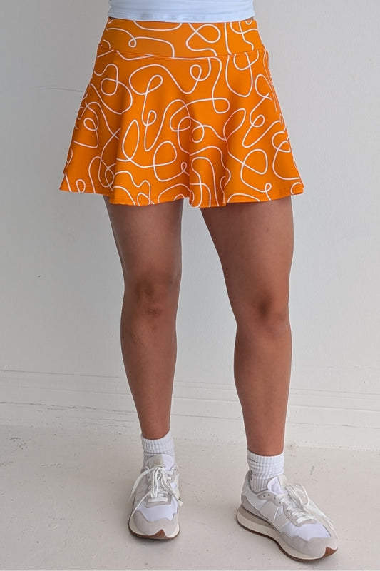 Full bodied orange miniskirt with scribbles print and built in shorts and pockets; great for gameday or hanging out with friends.