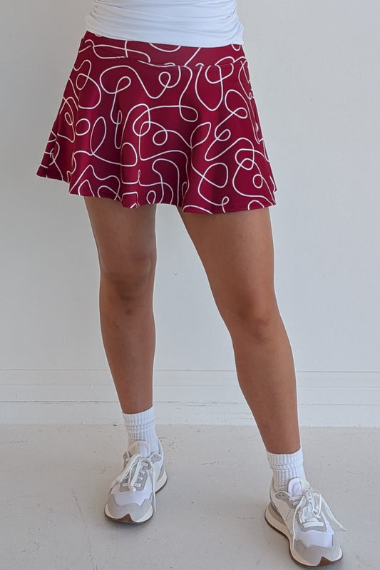Full bodied crimson miniskirt with scribbles print and built in shorts and pockets; great for gameday or hanging out with friends.