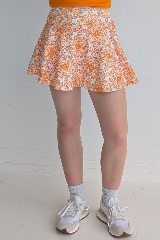 Full bodied orange miniskirt with scroll print and built in shorts and pockets; great for gameday or hanging out with friends.
