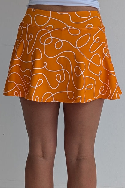 Full bodied orange miniskirt with scribbles print and built in shorts and pockets; great for gameday or hanging out with friends.