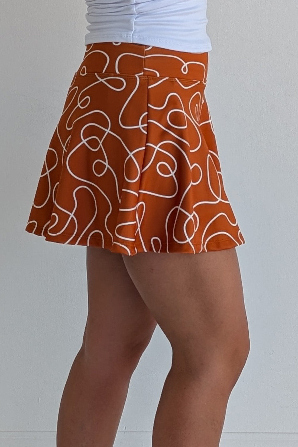 Full bodied burnt orange miniskirt with scribbles print and built in shorts and pockets; great for gameday or hanging out with friends.