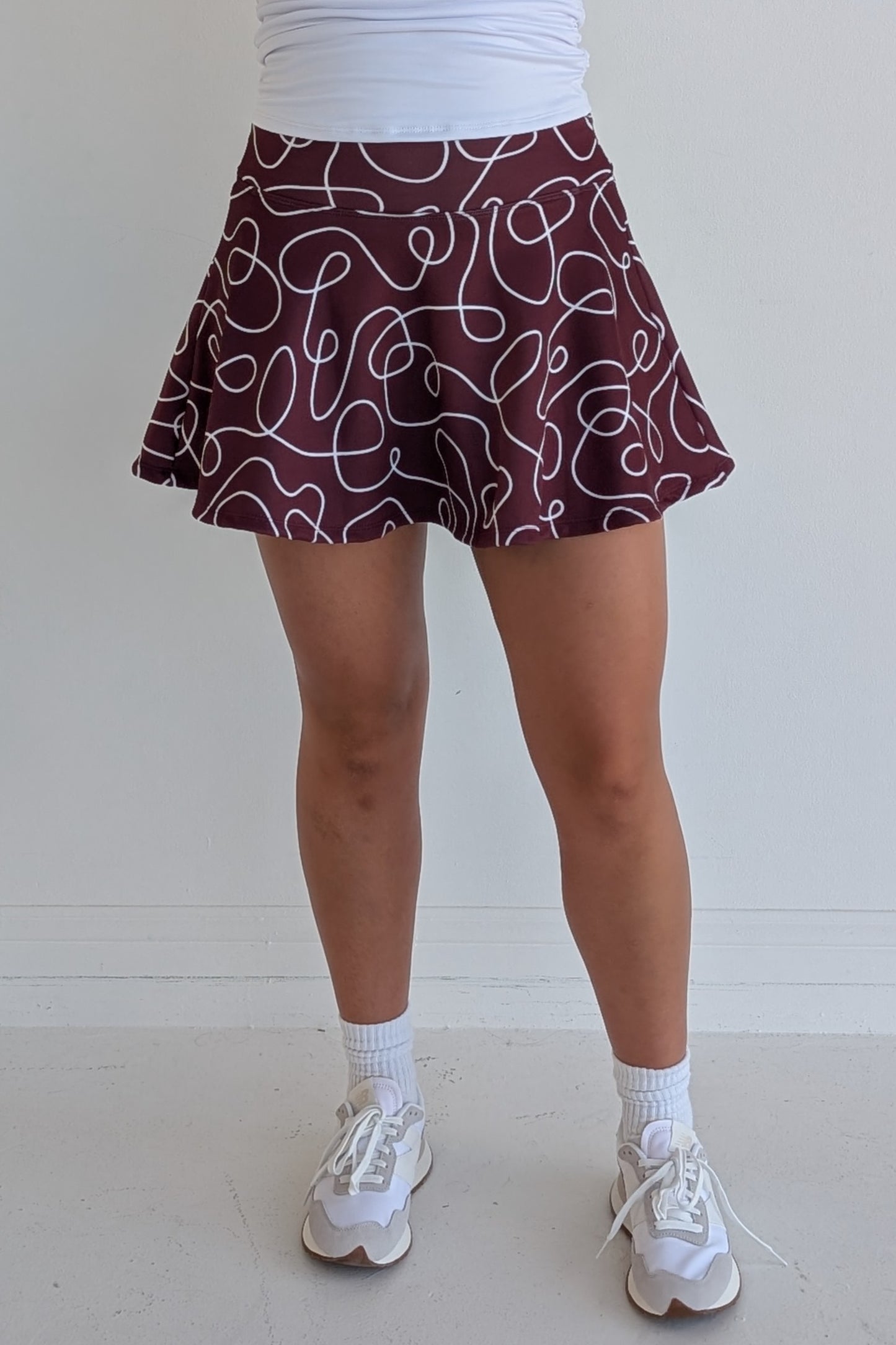 Full bodied maroon miniskirt with scribbles print and built in shorts and pockets; great for gameday or hanging out with friends.