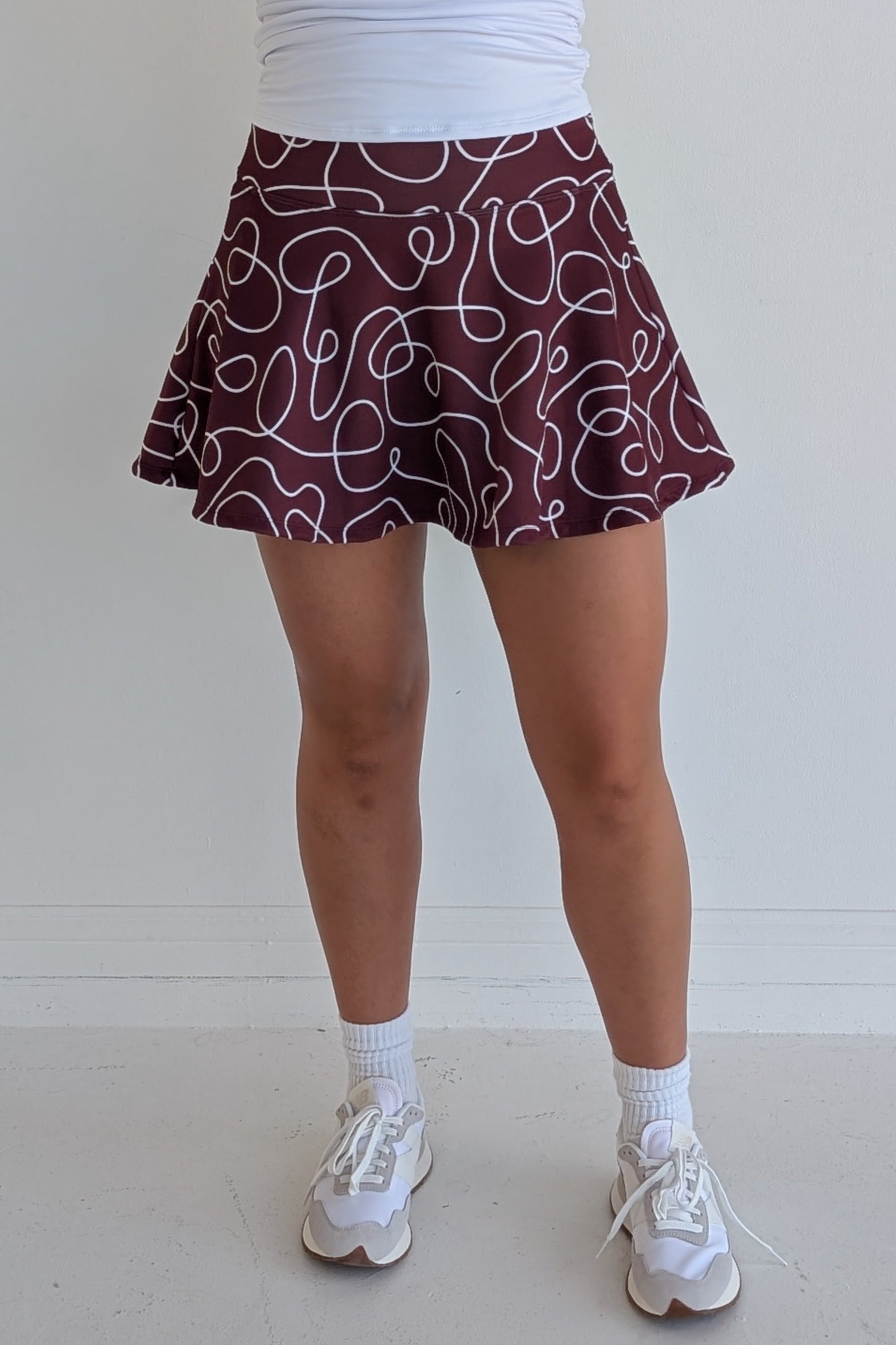 Full bodied maroon miniskirt with scribbles print and built in shorts and pockets; great for gameday or hanging out with friends.